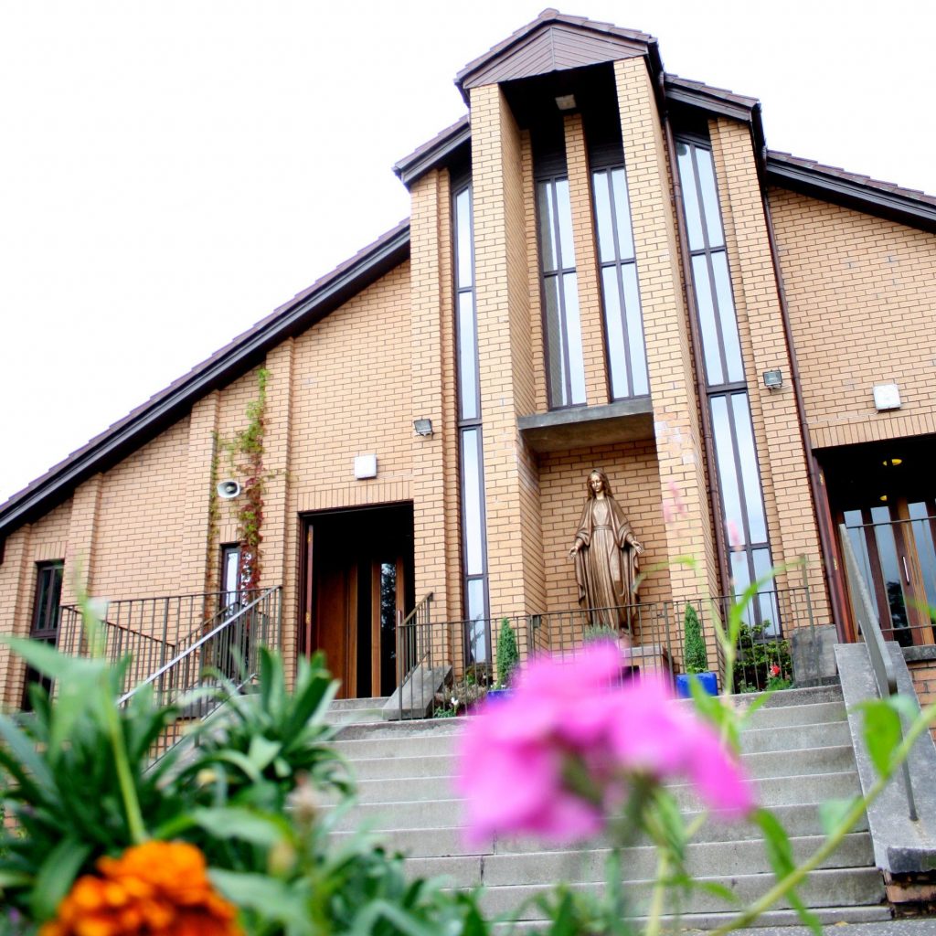 view of the church from below with pink and orange flowers in the foreground